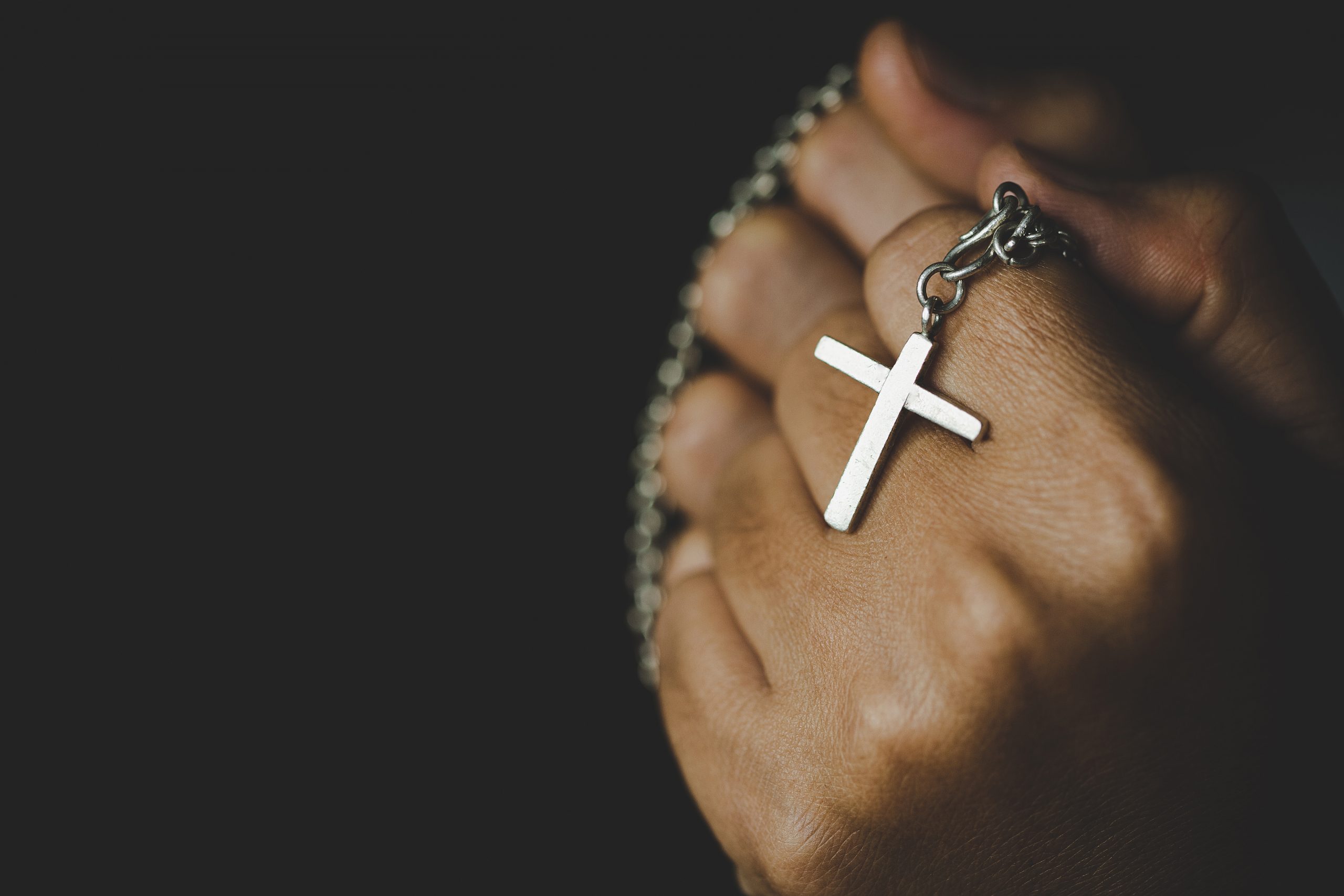 Women in religious concepts Hands praying to God while holding the cross symbol. Nun caught the cross in his hand. The human hand holds the holy cross and pray for God's blessings.